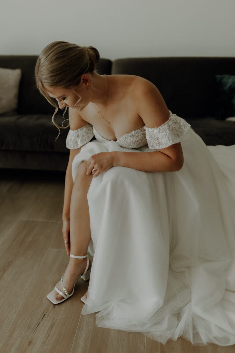 Braut zieht sich beim Getting Ready an ihrem Hochzeitstag ihre Brautschuhe an