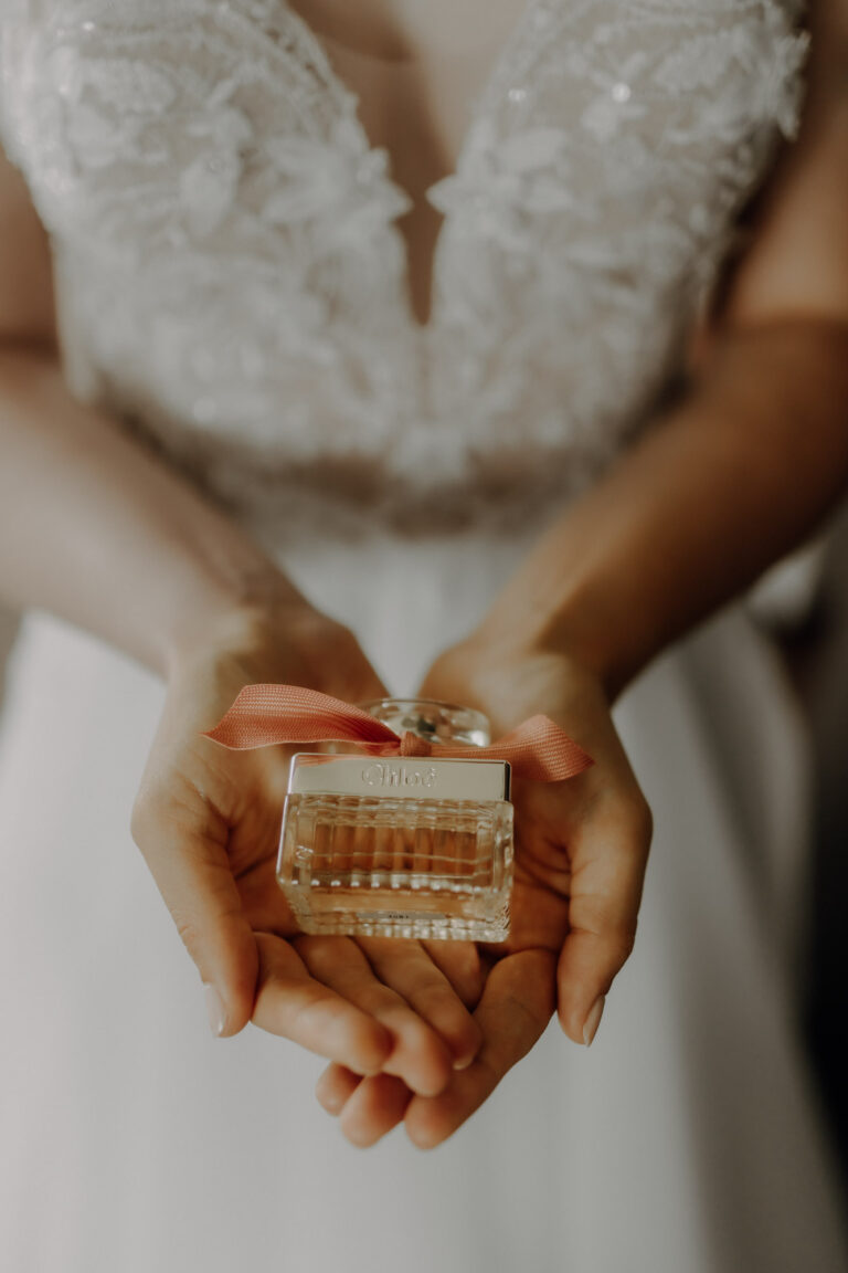 Detailaufnahme beim Getting Ready am Hochzeitstag von dem Parfüm, das die Braut in den Händen hält