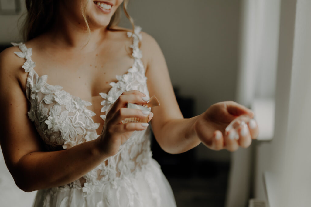 Braut sprüht sich Parfüm an Handgelenk beim Getting Ready