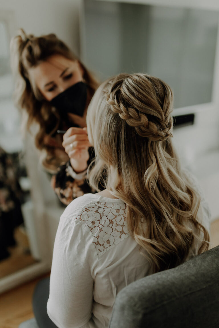Stylistin schminkt Braut an ihrem Hochzeitstag beim Getting Ready und macht ihre Hochzeitsfrisur