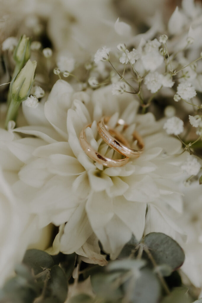 Eheringe liegen auf weißer Rose im Brautstrauß beim Detailshooting in Stuttgart
