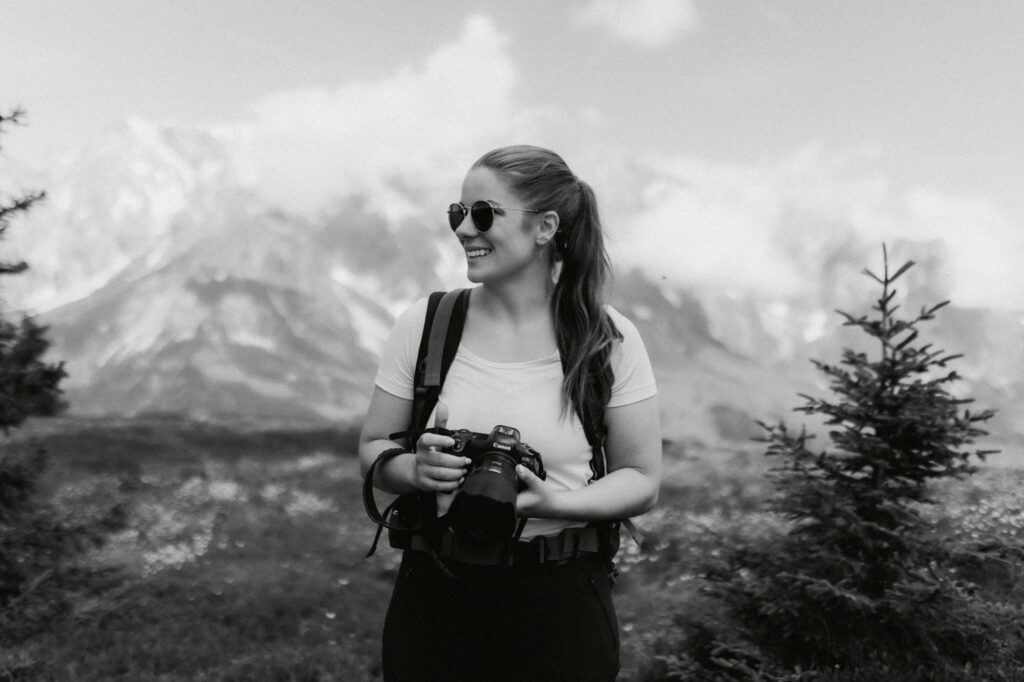 Fotograf und Hochzeitsfotograf Milena Sprung mit Kamera in der Hand in den Bergen